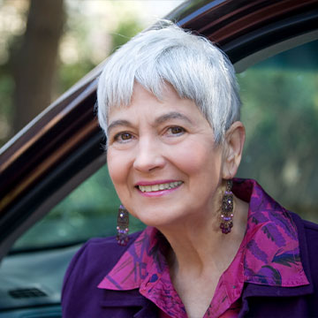 A woman smiles as she gets out of her car