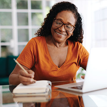 A woman smiling as she works on some paperwork on her computer. Links to Tangible Personal Property A woman smiling as she works on some paperwork on her computer. Links to Tangible Personal Property
